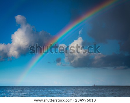 landscape view on cloudy sky with colorful rainbow at sea or ocean outdoor. Weather.