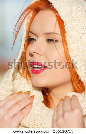 Winter fashion. Beauty face portrait red hair young woman in warm clothing white hood on head outdoor enjoying sunlight on sunny day.