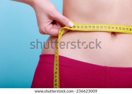 Time for diet slimming weight loss. Health care and healthy nutrition. Young fitness woman fit girl with measure tape measuring her waistline on blue green