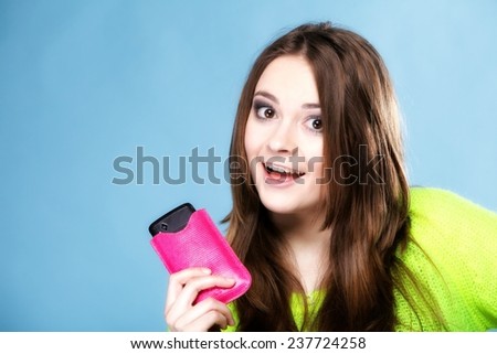 Happy girl young woman with mobile phone smartphone in pink cover studio shot blue background