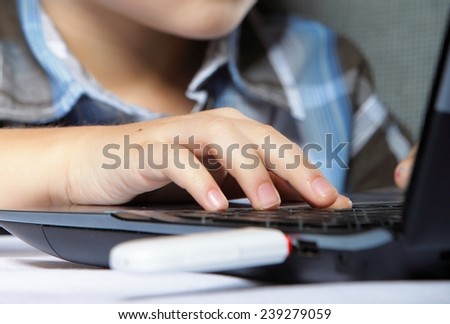 Cropped image of boy\'s schoolboy\'s hand typing on laptop keyboard