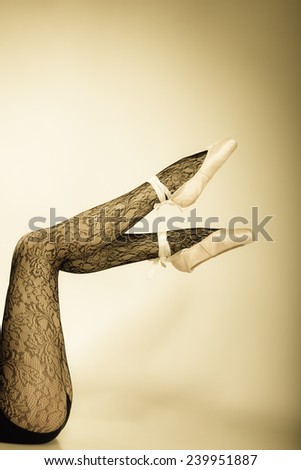 beautiful woman ballet dancer, part of body legs in shoes and black lace tights studio shot vintage aged tone