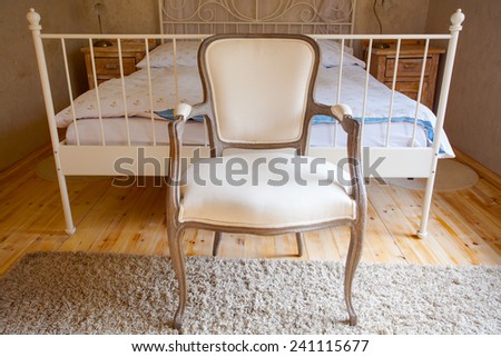 Interior of nice bedroom in vintage style. Room with comfortable double bed and retro chair. Design.