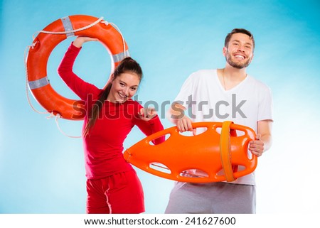 Accident prevention and water rescue. Young man and woman lifeguard couple on duty holding buoy lifesaver equipment having fun on blue