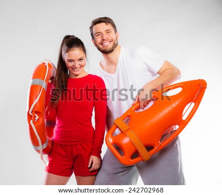 Accident prevention and water rescue. Young man and woman lifeguard couple on duty holding ring buoy float lifesaver equipment on gray