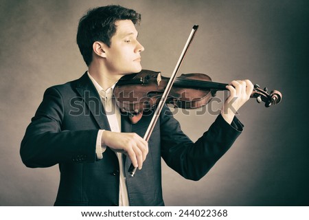 Art and artist. Young elegant man violinist fiddler playing violin on brown. Classical music.