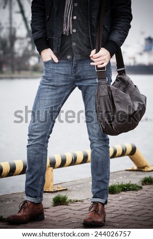 handsome man fashion model casual style with bag on street urban industrial background