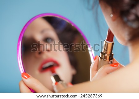 Cosmetic beauty procedures and makeover concept. Closeup part of woman face. Girl looking at mirror applying red lipstick lips makeup