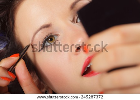 Closeup part of face, woman plucking eyebrows depilating with tweezers. Girl tweezing eyebrows.