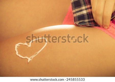 Skincare. Closeup of female body with heart shaped cream. Young woman girl taking care of her dry legs skin applying moisturizer lotion. Beauty treatment.