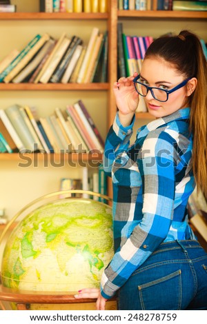 Education travel and geography concept. Young lovely woman female student looking through blue glasses in library with earth globe