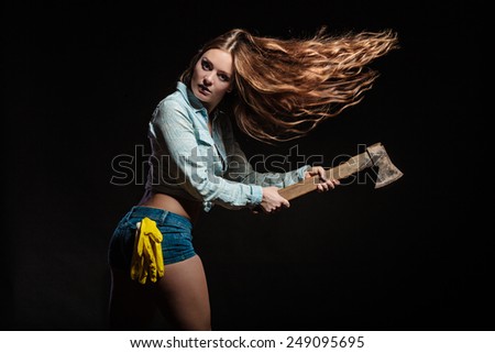 Woman in male specialities. Feminist sexy woman with tools hatchet. Blowing hair on black grey background in studio.