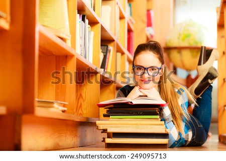 Education highschool concept. Female student charming long hair girl blue glasses working in college library with stack books. Indoor