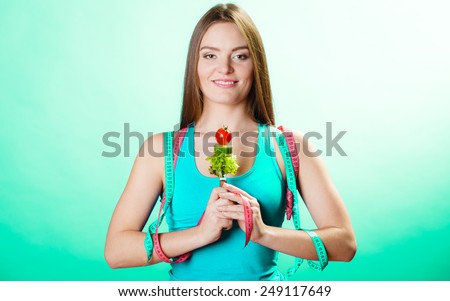 Weight loss and dieting concept. Sporty girl fitness woman holding fork with vegetarian food on blue green background in studio.