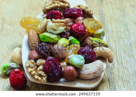 Healthy food organic nutrition. Closeup different varieties mix of dried fruits and nuts on wooden spoon.