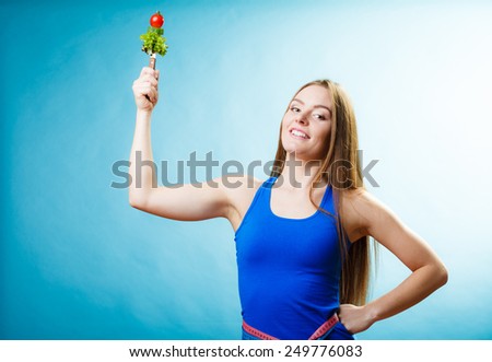 Slim body concept. Young woman fit girl with vegetarian food on blue background in studio.