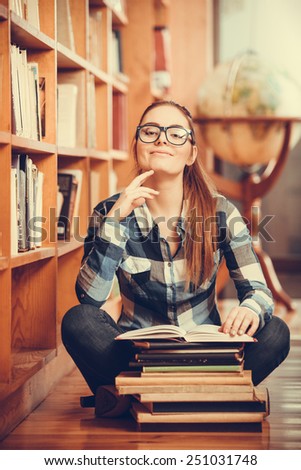 Education school concept. Clever female student hair ponytail girl glasses sitting on floor in college library with stack books. Indoor