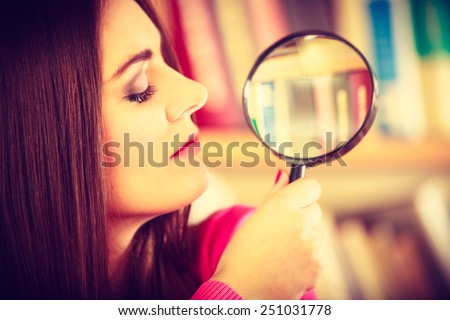 Exploration education concept. intelligent funny hipster student girl in library, woman holding magnifying glass loupe. Instagram filter