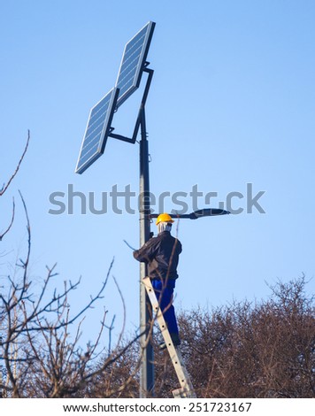 Photovoltaic panels renewable eco energy concept. Male engineer at work place, solar charging batteries on pole