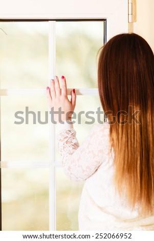 People and solitude concept. alone woman long hair looking dreaming through window back view indoor