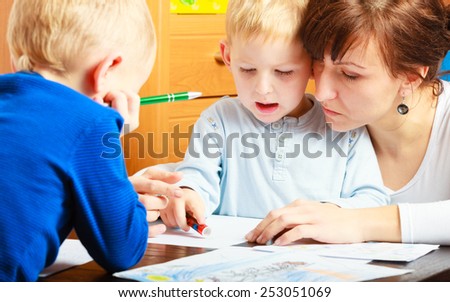 Family, children and happy people concept. Mother and sons drawing together, mom helping with homework