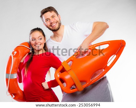 Accident prevention and water rescue. Young man and woman lifeguard couple on duty holding ring buoy float lifesaver equipment on blue