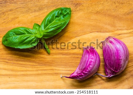 Healthy food. Organic garlic cloves and fresh basil leaves on rustic wooden table background