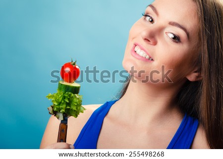Healthy eating and diet concept. Happy young woman holding vegetables on blue background. Studio shot.