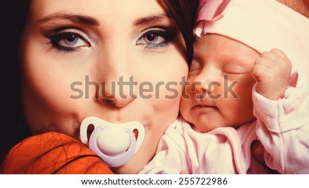 Parenting and love concept. Closeup funny mother with nipple in her mouth hugging one month old baby girl, closeup portrait