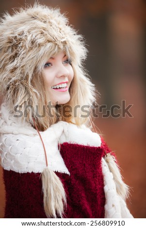 Winter fashion. Closeup smiling young woman wearing fashionable wintertime clothes fur cap outdoor portrait