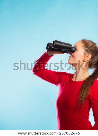 Young woman girl in red lifeguard on duty or tourist looking through binocular studio shot on blue