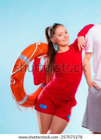 Accident prevention and water rescue. Young woman female smiling lifeguard on duty leaning on male arm holding lifesaver equipment on blue