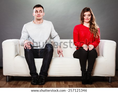 Shy woman and man. Guy sitting near attractive young woman on sofa and making hand gesture walking with finger to girl