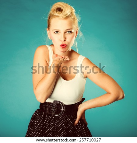 Retro pin up girl style. Young attractive woman sending hand kiss. Studio shot. Vintage photo.