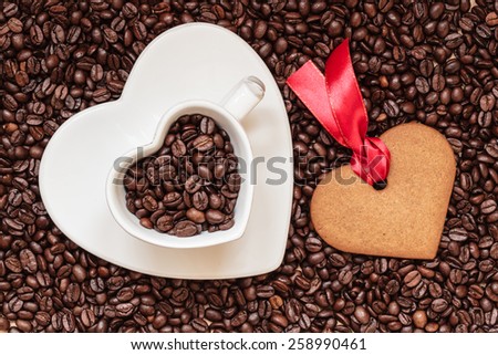 Coffee time concept. Heart shaped cup plate and cookie gingerbread on coffee beans background. Top view