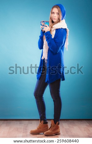 Hot beverage. Full length teen girl holding blue mug with drink tea or coffee. Woman warming herself studio shot