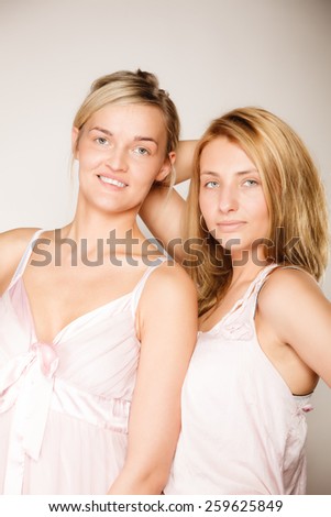 Attractive two blonde women with no makeup, fresh face with natural make up on gray