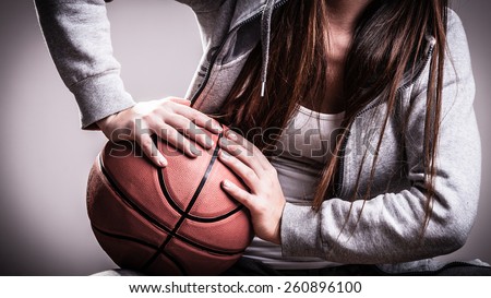 Young sporty woman teen girl long hair holding basketball on gray background
