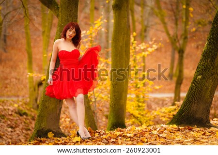 Full length fashionable elegant young woman in red dress outdoor relaxing walking in autumn fall park