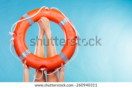 Accident prevention and water rescue. Life buoy ring lifebelt on female legs studio shot blue background