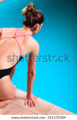 Sport active lifestyle. Sporty woman female swimmer muscular fit body preparing to jumping and diving into swimming pool  back view