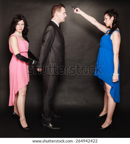 Scene of violence with firearm between men and women. Elegant lady holding gun aiming at man in suit on black and grey background in studio.