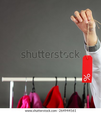 Good shopping sale concept. woman choosing clothes holding discount red label with percent sign in hand