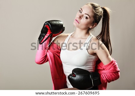 Feminist and emancipation idea. Woman in male occupation, training, boxing. Fit female fitness girl doing exercise on grey background.