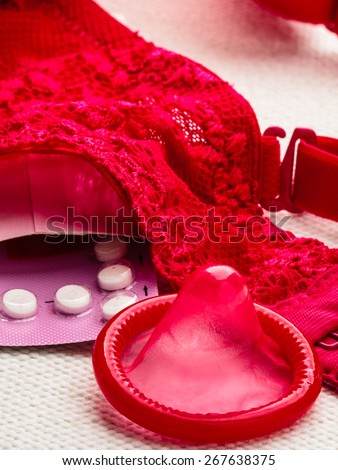 Healthcare medicine, contraception and birth control. Closeup oral contraceptive pills and condom with red lace bra lingerie.