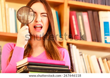 Investigation exploration education concept. Closeup intelligent funny student girl in library, woman holding magnifying glass loupe