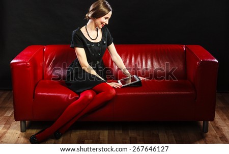 Technology internet business concept. Fashion woman retro style sitting with tablet on red couch