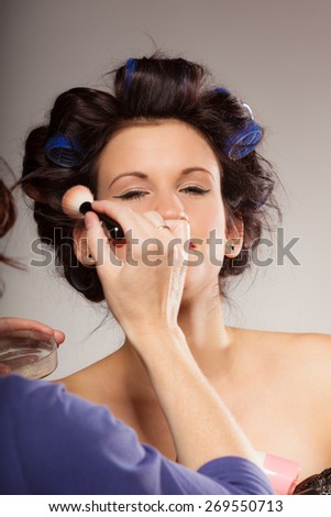Cosmetic beauty procedures and makeover concept. Makeup artist visagiste applying powder with brush on face of fashion model.