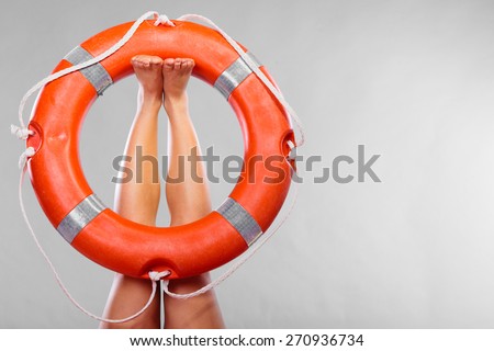 Accident prevention and water rescue. Life buoy ring lifebelt on female legs studio shot gray background