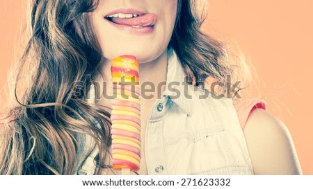 Summer vacation happiness concept. Funny cheerful woman covering eyes with straw hat eating popsicle ice cream orange background